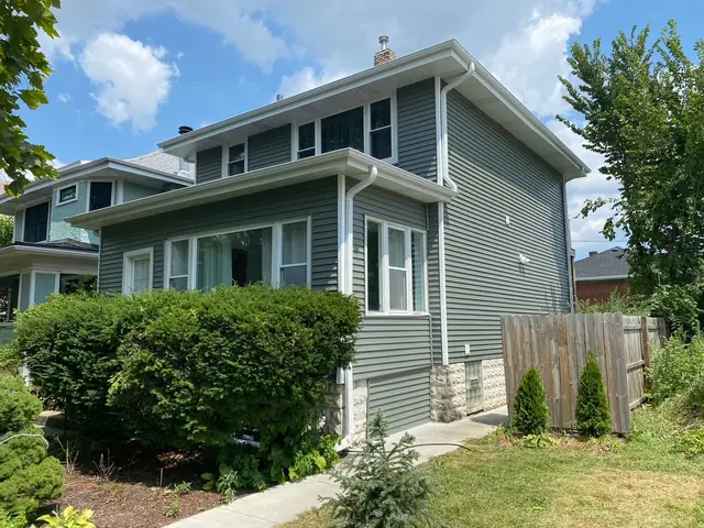 Two-story frame house finished in new sage-green siding with white trim